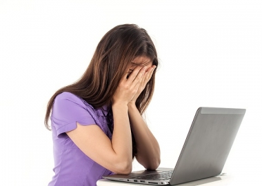 Woman with laptop and head in hands