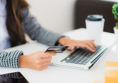 Woman at desk with credit card on laptop
