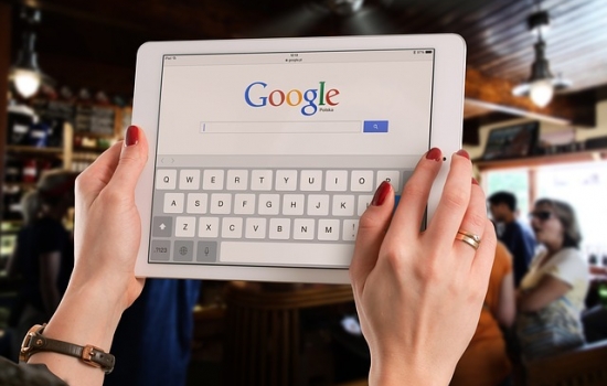 Woman holding tablet with Google homepage