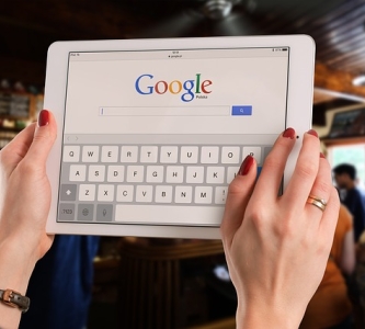 Woman holding tablet with Google homepage 